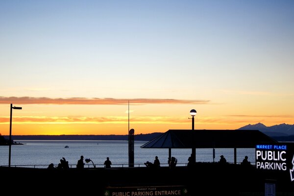 Pôr do sol no cais com silhuetas de pessoas