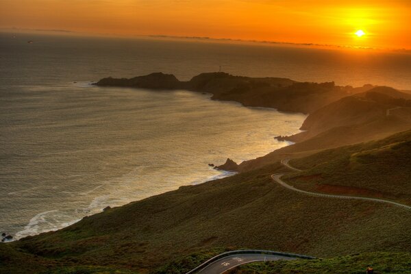 Sonnenuntergang am Meer mit Blick auf Berge und Wolken