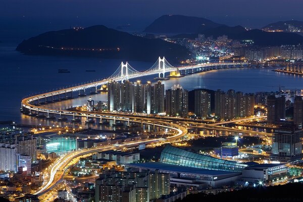 A road with a bridge over the strait at night