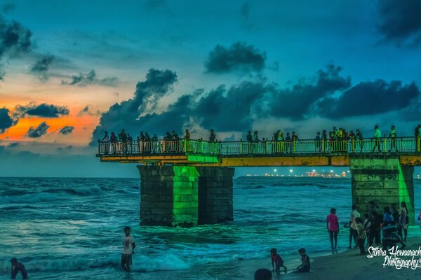 La gente en el puente Mira la puesta de sol