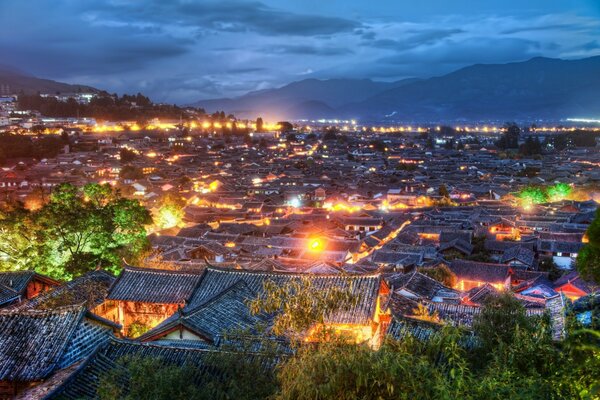 A small Asian city near the mountains is illuminated by night lights