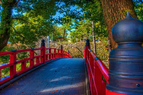 Puente rojo con adoquines de piedra en el parque