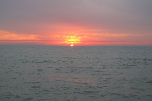 Il sole al tramonto tramonta nel mare grigio