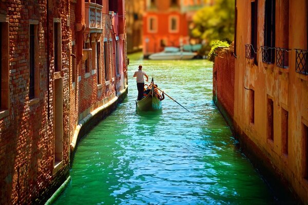 Ein Mann in einer Gondel fährt die Straße von Venedig entlang