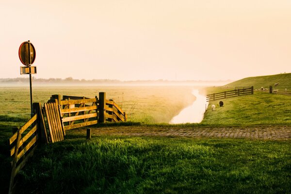 Campo con recinzione e fiume al tramonto