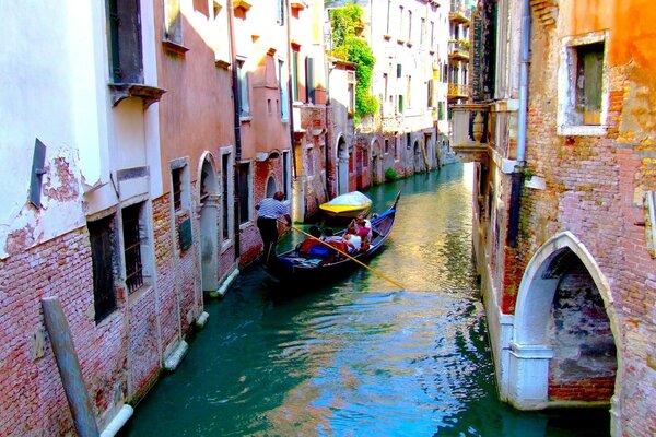 Ein Venezianer segelt mit einer Gondel durch die Straßen