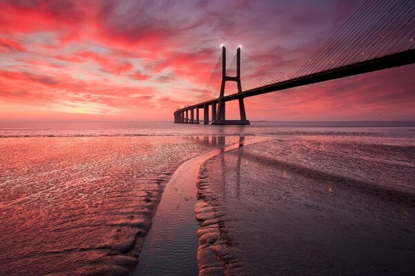 Red sunset of the ocean with a bridge