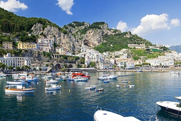 There are many boats near the rocky shore