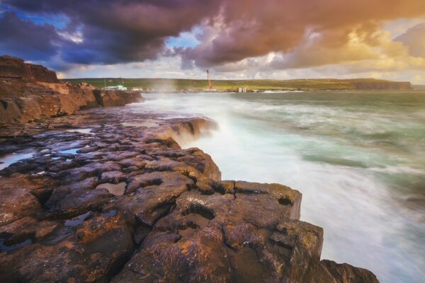 A rapidly rushing stream cascading over boulders, a lone lighthouse is visible on the edge of this stream