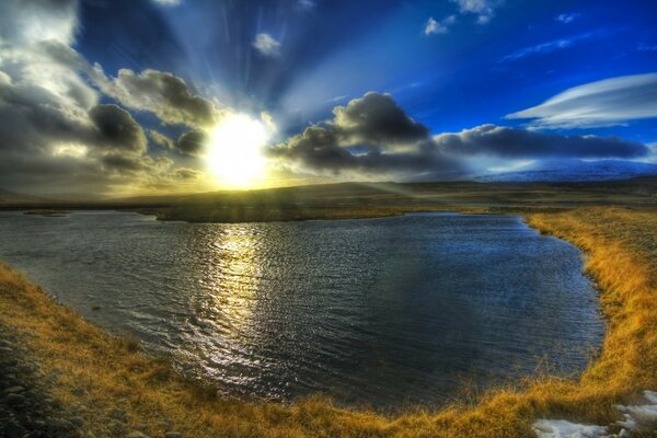 The sun breaking through the clouds over the lake