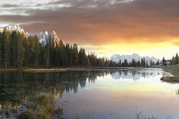 Alba sullo sfondo di un lago, montagne e boschi. Gratificazione delle montagne nel lago