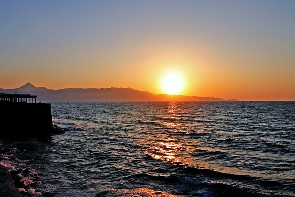 Hermosa puesta de sol junto al mar. Rocas en el horizonte