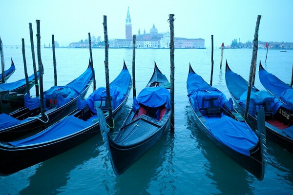 Góndolas en el fondo de Venecia en tiempo nublado