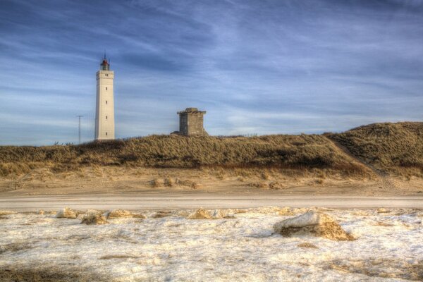 A white lighthouse under a blue sky