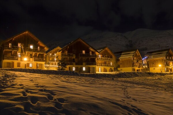 Vista invernale serale di piccole case europee in montagna