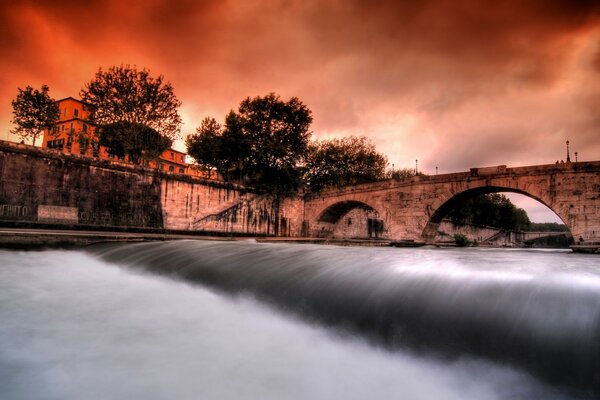 European arch bridge over a river with a waterfall