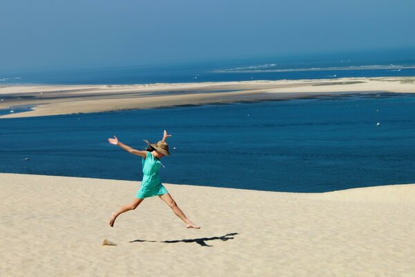 A joyful girl runs through the sand. Vacation by the sea