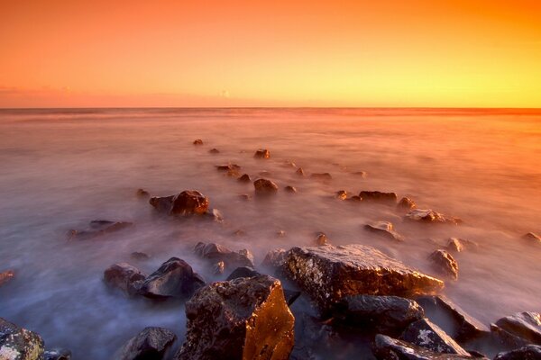 Belo pôr do sol no nevoeiro na praia rochosa