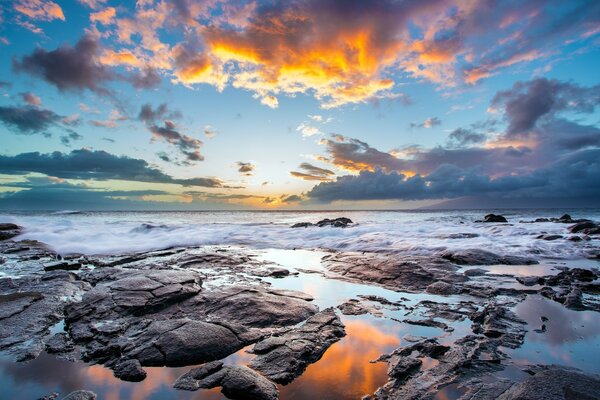 As ondas rolam na costa rochosa durante o pôr do sol