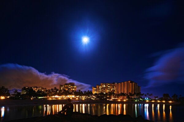 The moon shines brightly over the night city