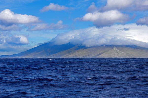 Weiße Wolken umhüllen die Insel im Meer