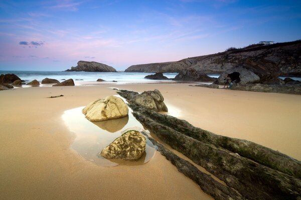 Playa de arena con grandes piedras