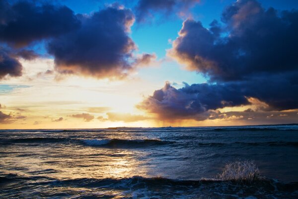 The bright sun peeks out between the clouds over the sea