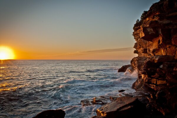 Côte rocheuse de la mer sur fond de coucher de solesignement