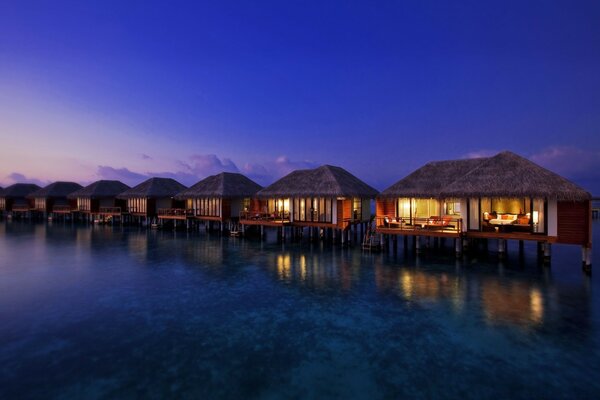 Houses on stilts in the sea are reflected in the water