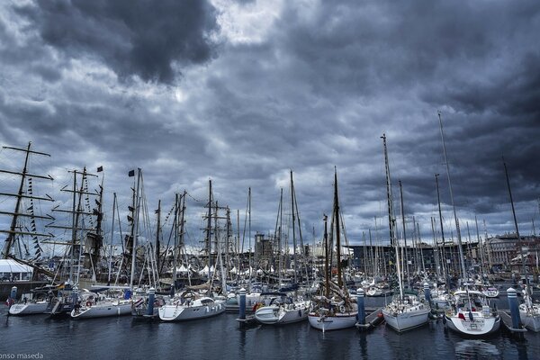 Harbor with yachts and sailboats on a gray sky background