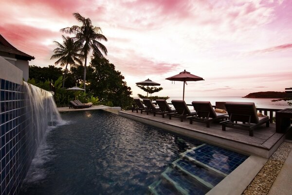 Cielo rosa sobre la piscina y las sombrillas de playa